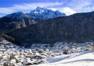 a town in the snow with mountains in the background at Rifugio TEA Dolomiti in Caviola