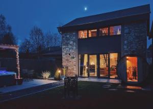 a house with glass doors and a patio at night at L'école Buissonnière - Suite Bien-être 2 personnes in Vielsalm