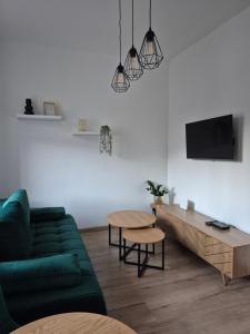 a living room with a green couch and a table at Apartament Moniuszko in Jedlina-Zdrój