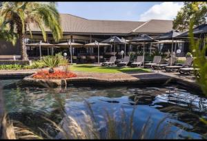a resort with a pool with chairs and a building at Trinity S t a y in Benoni