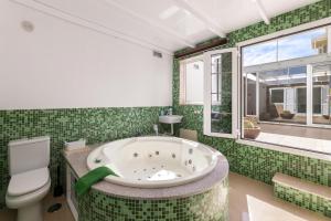 a green tiled bathroom with a tub and a toilet at Serenity Villa Lanzarote by Beyond in San Bartolomé +31 photos
