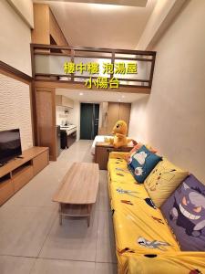 Una sala de estar con un sofá amarillo y una mesa. en cookies溫泉湯屋, en Jiaoxi