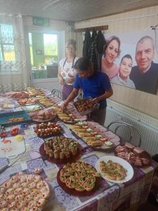 a group of people standing around a table of food at Cabana Scobinți  +3 photos