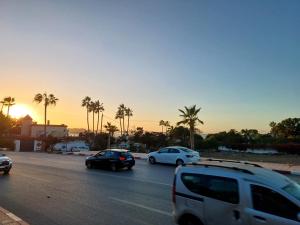 a group of cars driving down a street with palm trees at الشروق 2 résidence chourouk 2 in Mansouria
