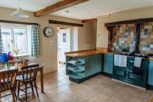 a kitchen with blue cabinets and a table and a dining room at Hogchester Cottage in Bridport