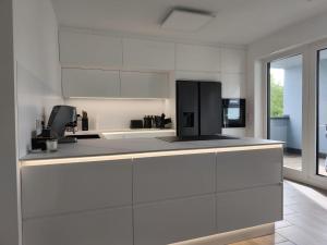 a kitchen with white cabinets and a black refrigerator at Annas Ferienwohnung in Wallerfangen