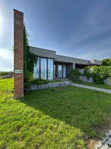 Stantsiya KachretiVilla 39, Kachreti Ambassadori Golf Resort的一栋房子，有一根砖柱和一个草坪院子。