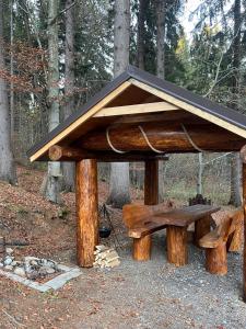 una mesa de picnic de madera y un banco en un bosque en Chata u Zbojníka, en Oravský Podzámok