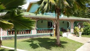 a house with a palm tree in front of it at Villa Bedier Self-catering Apartments in Baie Sainte Anne
