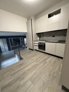 een keuken met witte kasten en een houten vloer bij Il Paese delle Vacanze by Elisa in Omegna
