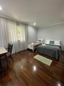 a bedroom with a bed and a chair and a table at Quarto amplo e confortável in Sao Paulo