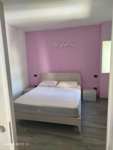 een slaapkamer met een wit bed en een paarse muur bij Il Paese delle Vacanze by Elisa in Omegna +2 foto's