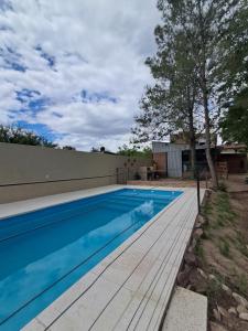 a swimming pool with a wooden deck next to a house at Un lugar en el mundo in Mina Clavero