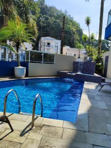 une piscine avec des chaises longues à côté d'un bâtiment dans l'établissement Hotel Guarumar, à Guarujá 30 autres photos
