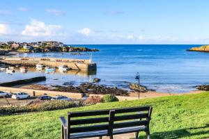 a bench sitting on a hill overlooking a body of water at 2 Harbour Lights in Cemaes Bay