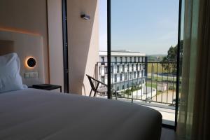 a bedroom with a bed and a balcony with a view at Oporto Fly Hotel in Maia