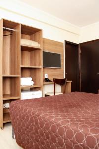 une chambre avec un lit et un bureau avec un écran dans l'établissement Hotel Guarumar, à Guarujá