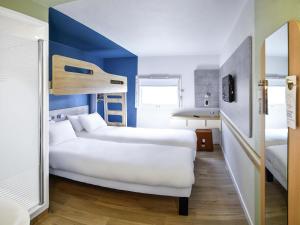a hotel room with two beds and a blue wall at ibis Budget Le Treport Mers Les Bains in Mers-les-Bains +48 photos