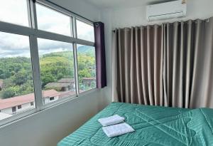 a bedroom with a bed and a large window at อิงเขาค้อ in Campson