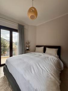 a bedroom with a large white bed and a window at Mountain View Apartments in Kalavrita