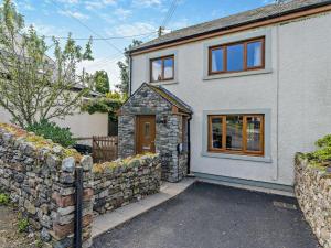 a white house with a stone wall at 3 Bed in Uldale 95374 in Uldale