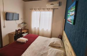 a bedroom with a bed with a red and white blanket at Pousada Lira Praieira Paraty in Paraty