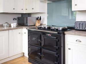 a black stove in a kitchen with white cabinets at 4 Bed in Borrowdale SZ219 in Grange +13 photos