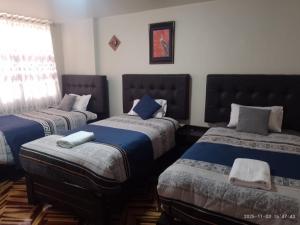 a bedroom with three beds with blue and gray sheets at San Antonio hotel in Puno