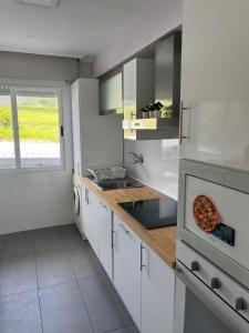a kitchen with white cabinets and a pizza on the counter at APARTAMENTOS URDAIBAI 4 in Busturia +8 photos