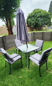 a table and chairs and an umbrella on the grass at Felinga Guest House in Centurion