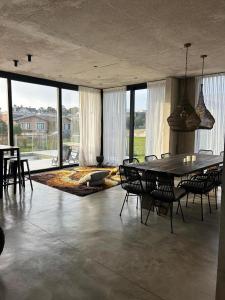 a dining room with a table and chairs and windows at Casa Rumenco Joven mdq in Mar del Plata