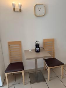 a table and two chairs and a clock on a wall at Clos d'AIX studio 5 in Aix-en-Provence
