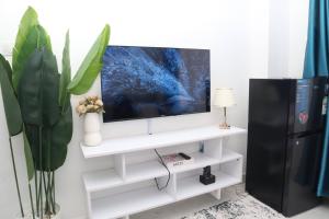 a living room with a tv on a white shelf at Makasembo Cozy Serenity in Kisumu
