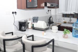 a kitchen with a counter with four white chairs at Makasembo Cozy Serenity in Kisumu