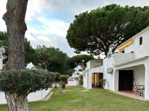 un edificio blanco con un patio con un árbol en Refúgio junto à falésia, en Olhos de Água