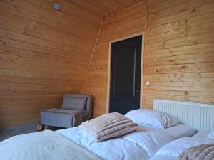 two beds in a room with a chair and a door at Escape Remeti - Aframe by the River in Remeţi