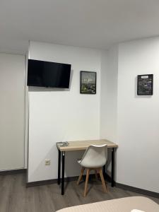 a desk with a chair and a television on a wall at Pensión Ferreiriño in Quiroga