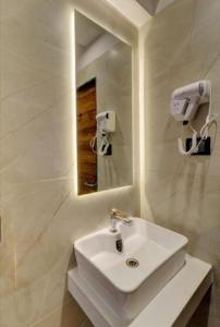 Un baño con un lavabo blanco y un espejo. en Hotel Sunshine At Delhi Airport, en Dwarka, Nueva Delhi