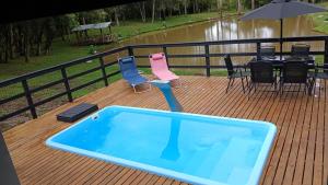einen Pool auf einer Terrasse mit Stühlen und einem Tisch in der Unterkunft Pousada Caminho do Lago in Rio Rufino