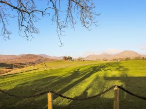 een hek in een veld met bergen op de achtergrond bij The Peacock Roost - Uk46297 in Brynkir +1 foto
