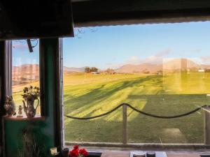 een raam met uitzicht op een golfbaan bij The Peacock Roost - Uk46297 in Brynkir