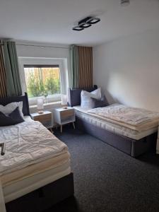 ein Hotelzimmer mit zwei Betten und einem Fenster in der Unterkunft Nahe Kiel, 4 Betten, 2 Schlafzimmer Parkplatz, Terrasse, 3km zum Strand in Osdorf