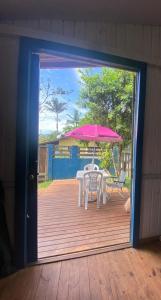 een open deur naar een terras met een tafel en een parasol bij Cabana da palmeira in Piçarras