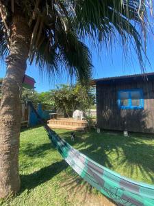 een hangmat hangend aan een palmboom naast een huis bij Cabana da palmeira in Piçarras +3 foto's