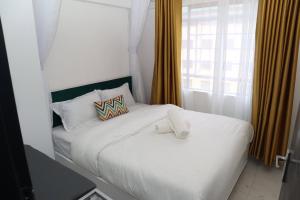 a white bed with two pillows and a window at Makasembo Cozy Serenity in Kisumu