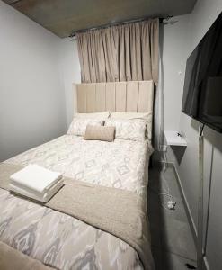 a bedroom with a bed and a flat screen tv at Felinga Guest House in Centurion +9 photos