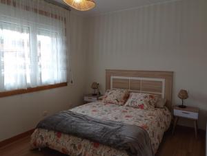 ein Schlafzimmer mit einem Bett und zwei Fenstern und einer Lampe in der Unterkunft Casa Playa Meira in Moaña