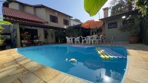 a swimming pool in front of a house at Aconchego e diversão em Peruíbe sobrado com estrutura completa para sua família ar condicionado, churrasqueira ,academia, cervejeira, piscina in Peruíbe