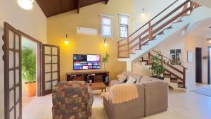 a living room with a couch and a tv at Aconchego e diversão em Peruíbe sobrado com estrutura completa para sua família ar condicionado, churrasqueira ,academia, cervejeira, piscina in Peruíbe
