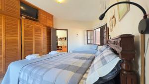 a bedroom with a bed and a tv on the wall at Aconchego e diversão em Peruíbe sobrado com estrutura completa para sua família ar condicionado, churrasqueira ,academia, cervejeira, piscina in Peruíbe +71 photos